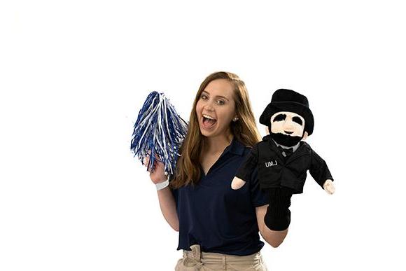 person with mascot plush and pom pom in hands.